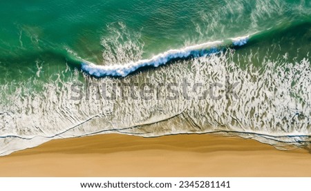 Aerial view of beach with waves crashing into the sand. High resolution.