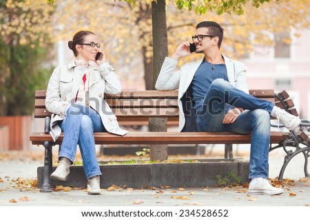 Two people talking on the phones in a park