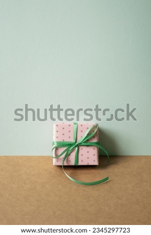 Pink dot pattern gift box on brown table. mint green wall background. copy space