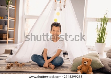Photo of cute adorable boy son have free time on holidays playing with toys in homemade tent playroom interior