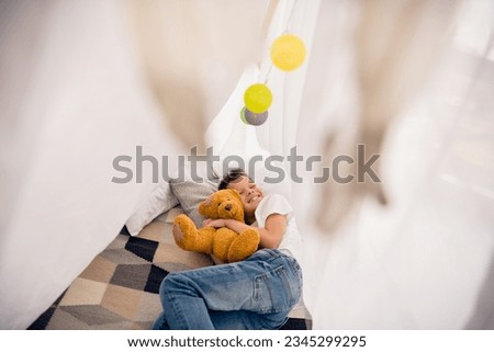Photo of positive boy nap in homemade tent playing with toys in modern playroom indoors