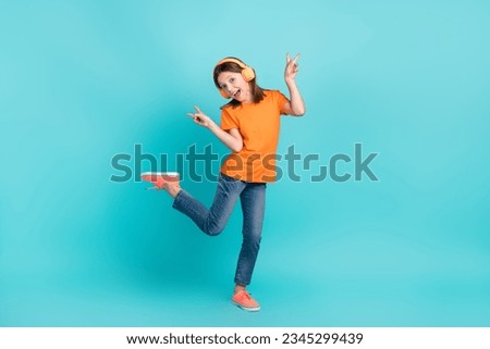 Photo of energetic crazy cute girl wear stylish orange clothes hand demonstrate v-sign good mood isolated on cyan color background