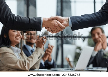 Handshake in agreement against young business people in board room meeting