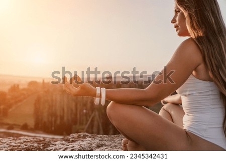 Well looking middle aged woman with long hair, fitness instructor in leggings and tops doing stretching and pilates on the rock near forest. Female fitness yoga routine concept. Healthy lifestyle