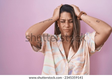 Blonde woman standing over pink background suffering from headache desperate and stressed because pain and migraine. hands on head.  Royalty-Free Stock Photo #2345359141