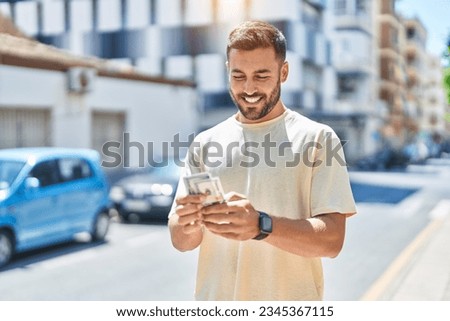 Young hispanic man smiling confident counting dollars at street Royalty-Free Stock Photo #2345367115