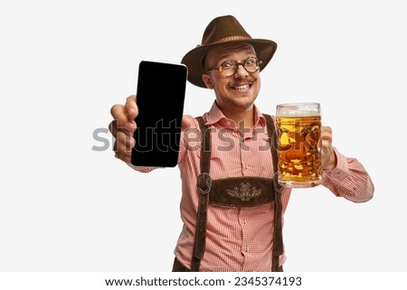 Happy. Young mustache man, waiter in traditional Bavarian ot German outfit show phone with blank screen. Celebration, oktoberfest, festival, trades, graphs concept. Copy space for ad. Banner