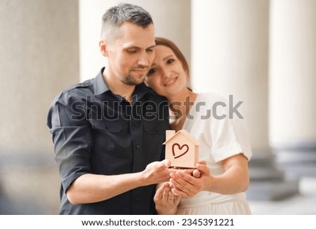 Cute young couple holding a small model house, home loan concept, renting or buying real estate.