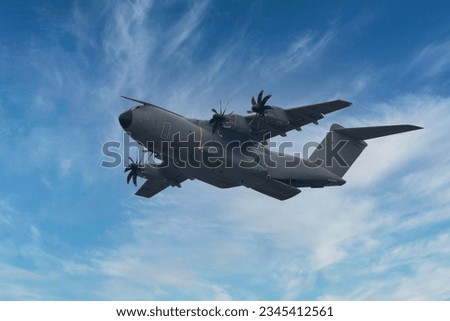 An Airbus A400M Atlas military transport aircraft flying high in the blue sky Royalty-Free Stock Photo #2345412561