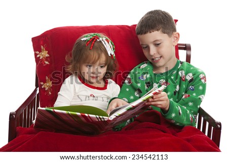 Christmas stories.  Brother and sister in bed enjoying a Christmas story together.  Isolated on white.