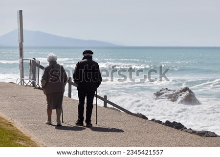 elderly couple walking on the promenade by the beach Royalty-Free Stock Photo #2345421557