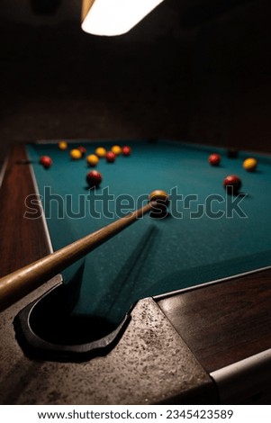 A vertical footage of a billiard table with balls and cue in a dark room Royalty-Free Stock Photo #2345423589