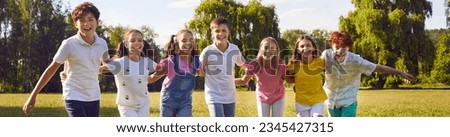 Happy children standing in a line together outside and smiling in the park on holidays enjoying spending time in a summer camp. Portrait of a hugging kids looking outdoor at the camera. Banner.