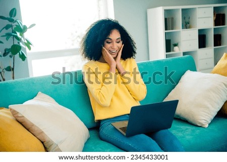 Photo of pretty astonished girl sit sofa use netbook hands touch cheeks living room house indoors