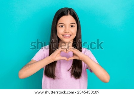 Portrait of charming little cute schoolgirl showing heart symbol sympathy donation support poor families isolated on cyan color background