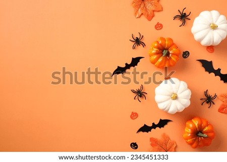 Happy Halloween holiday concept. Halloween decorations, pumpkins, spiders, maple leaves on orange background. Minimal style. Flat lay, top view.