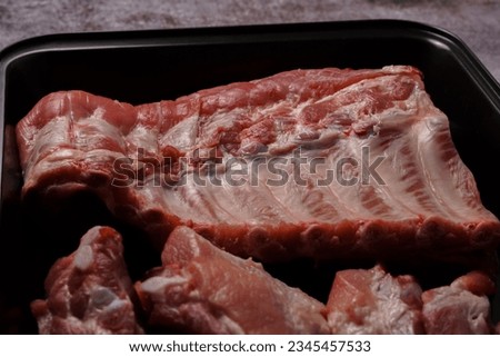 raw pork ribs on a black tray ready for oven roasting