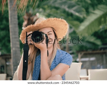 Photography and travel. A young woman in a hat holds a camera