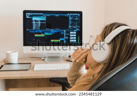 Blonde woman with headphones working on the computer at home, editing a video