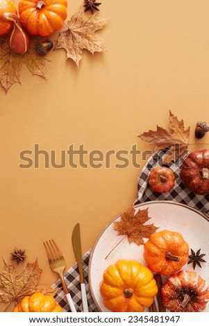 Embrace fall with a table setting. Top view vertical shot of plate, cutlery, tablecloth, bright pumpkins, anise, acorns, maple leaves on pastel brown background with empty space for promo or text