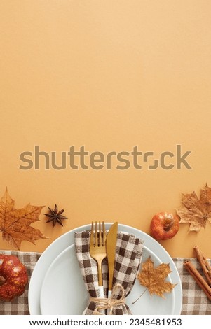 Captivating autumnal decor concept. Top view vertical shot of plate, cutlery, napkin, tablecloth, pumpkins, cinnamon sticks, anise, autumn leaves on pastel brown background with space for ads or text