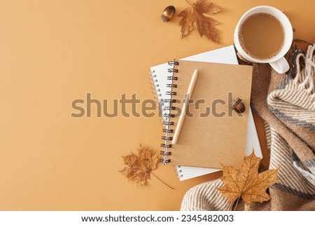 Enjoy the warmth of fall at home. Top view photo of warm chocolate, comfortable blanket, pen, notebook, acorns, autumn leaves on pastel brown background with empty space for advert or message