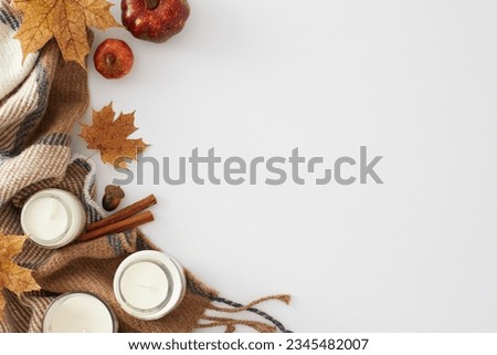 Create a captivating and autumn-themed setup. Top view shot of candles, warm blanket, pumpkins, acorn, cinnamon sticks, maple leaves on white background with empty space for advert or message Royalty-Free Stock Photo #2345482007