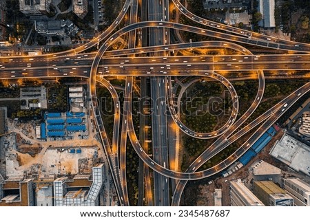 Aerial shot of a bustling city intersection at night with cars driving on the illuminated roads