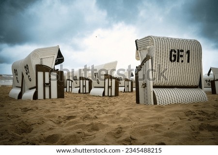Roofed wicker beach chairs at the baltic sea beach, coast at the island of Usedom in Germany, storm and rain over the brackish water, high waves, storm warning