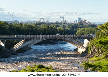 The Chaudière River flowing under an overpass bridge during a summer late afternoon, with the Pierre-Laporte and Québec bridges in the background, Lévis, Quebec, Canada