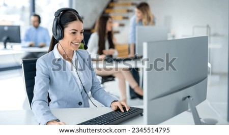 Portrait of smiling service desk analyst with headset answering client's questions and resolving client's issues in call center. Royalty-Free Stock Photo #2345514795