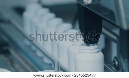 4K conveyor with moving empty white plastic tubes on the production line and filling with capsules. Automatic machine in the factory. Modern High-Tech Pharmacology Factory. Close Up, DOF Royalty-Free Stock Photo #2345523497