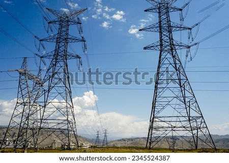 A low angle view of high voltage powerlines on the field Royalty-Free Stock Photo #2345524387