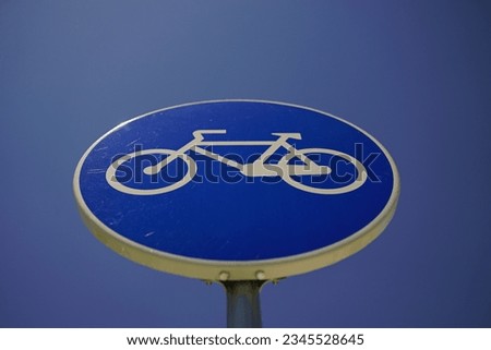 A low angle shot of a bicycle sign against a blue sky background