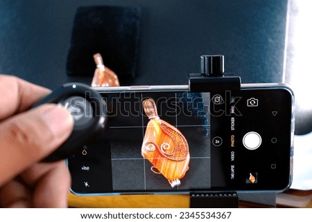 A person taking a picture of a figurine with a smartphone