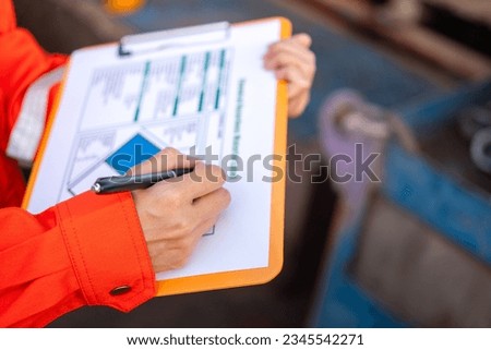 Action of a supervisor is using a pen to writing on chemical hazardous material paper form to rating the risk. Industrial safety working. Selective focus.