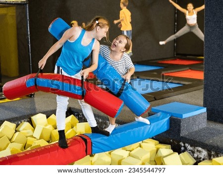Active excited child school girls having fun and fighting with inflatable logs in amusement center