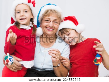 children with grandmother in santa hats preparing to Christmas