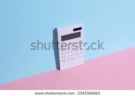 White calculator on blue-pink background with shadow. Business and finance concept. Creative composition
