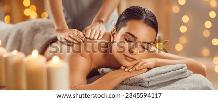Beautiful young woman enjoying massage in spa salon. Relaxed brunette girl lying on massage bed with closed eyes during spa treatment procedure. Beauty treatment, skin care, wellbeing Royalty-Free Stock Photo #2345594117