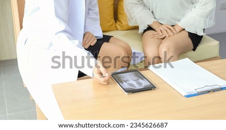 Asian woman patient sitting with doctor about her illness and showing x-ray results 
