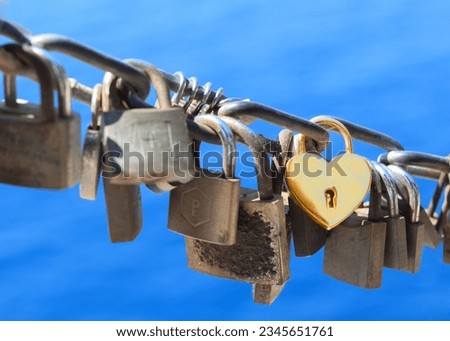 Yellow heart shaped padlock as symbol of eternal love hanging on chain with sea view. Old rusty love locks on chain. Vintage colorful padlocks heart shaped on blue background. Couple. Clip art. Cards
