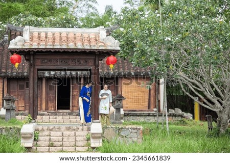 Vietnamese Woman and Caucasian woman in Ao Dai Dress visit the old temple outdoor