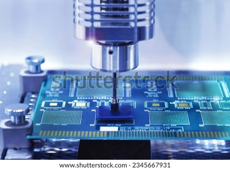 Close up technological process of assembly chip components on pcb board. Automated machine inside at industrial Royalty-Free Stock Photo #2345667931