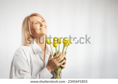 Beauty young blonde happy woman with bouquet of yellow tulips on white background. The concept of a holiday and a gift for a lady and a girl. . Copy space
