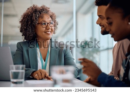 Happy insurance agent offering an agreement to young couple during a meeting in the office. Royalty-Free Stock Photo #2345695143
