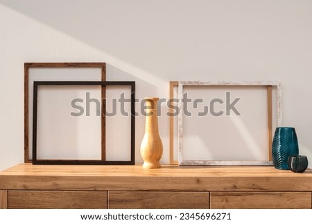 Wooden frames decorations on the wooden chest of drawers inside the house. Minimal art in modern home interior.