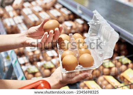 Hands of woman with packing eggs in supermarket Royalty-Free Stock Photo #2345698325