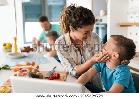 Close-up photo of mother and son being joyful in the kitchen while smiling at each other. Loving mother bonding with her child. Royalty-Free Stock Photo #2345699721