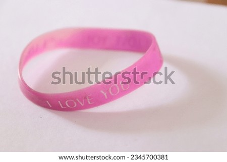A Friendship band or bracelet made up of rubber in gradient of yellow and orange and I Love You written on it in a white isolated Background 